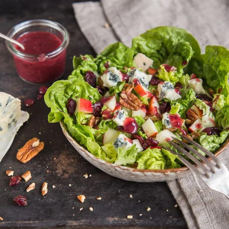 a salad with apples, cranberry sauce and pecans is on the table