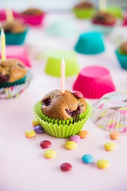 Kerze auf muffin mit bunten süßigkeiten auf rosa hintergrund ...