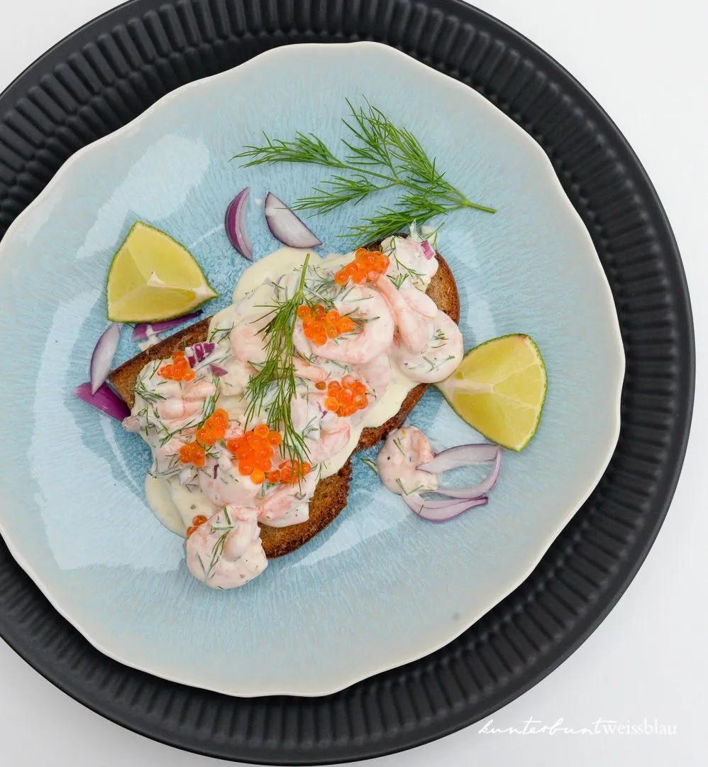 a blue plate topped with bread covered in crab and carrots next to ...