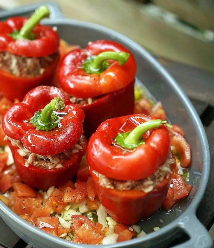 several stuffed red peppers in a pan on top of a wooden table with ...