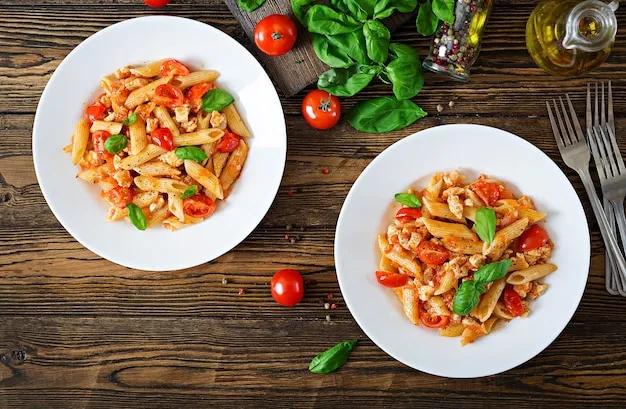 Penne pasta in tomatensauce mit huhn, tomaten, mit basilikum dekoriert ...