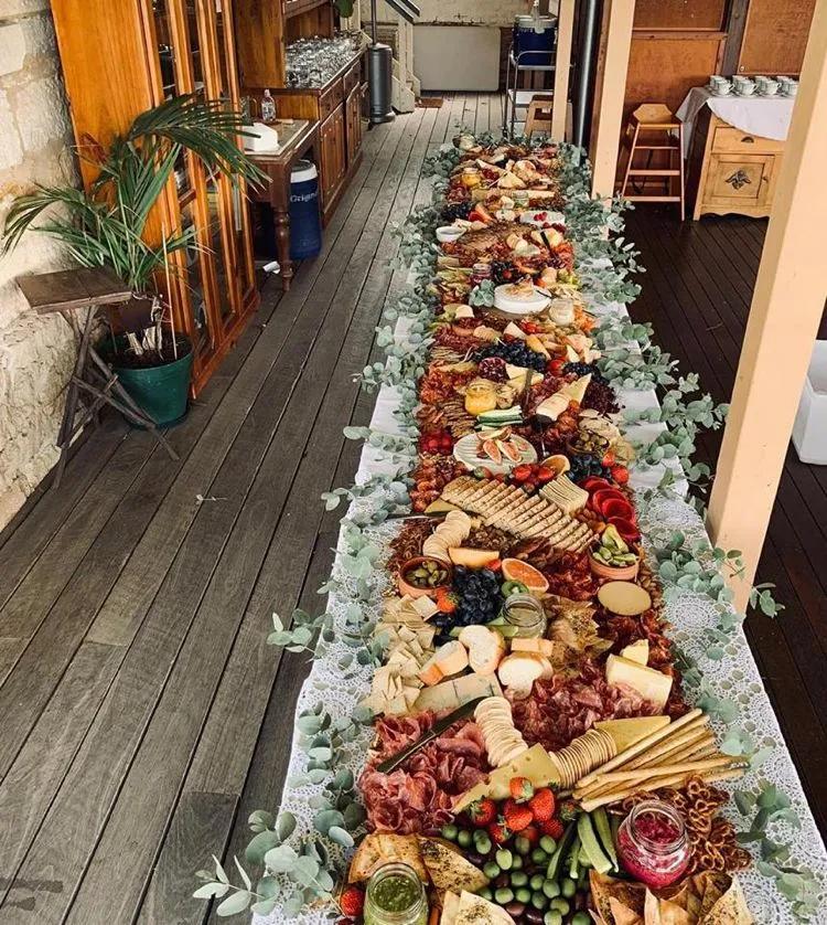 a long table filled with lots of food on top of a wooden floor next to ...