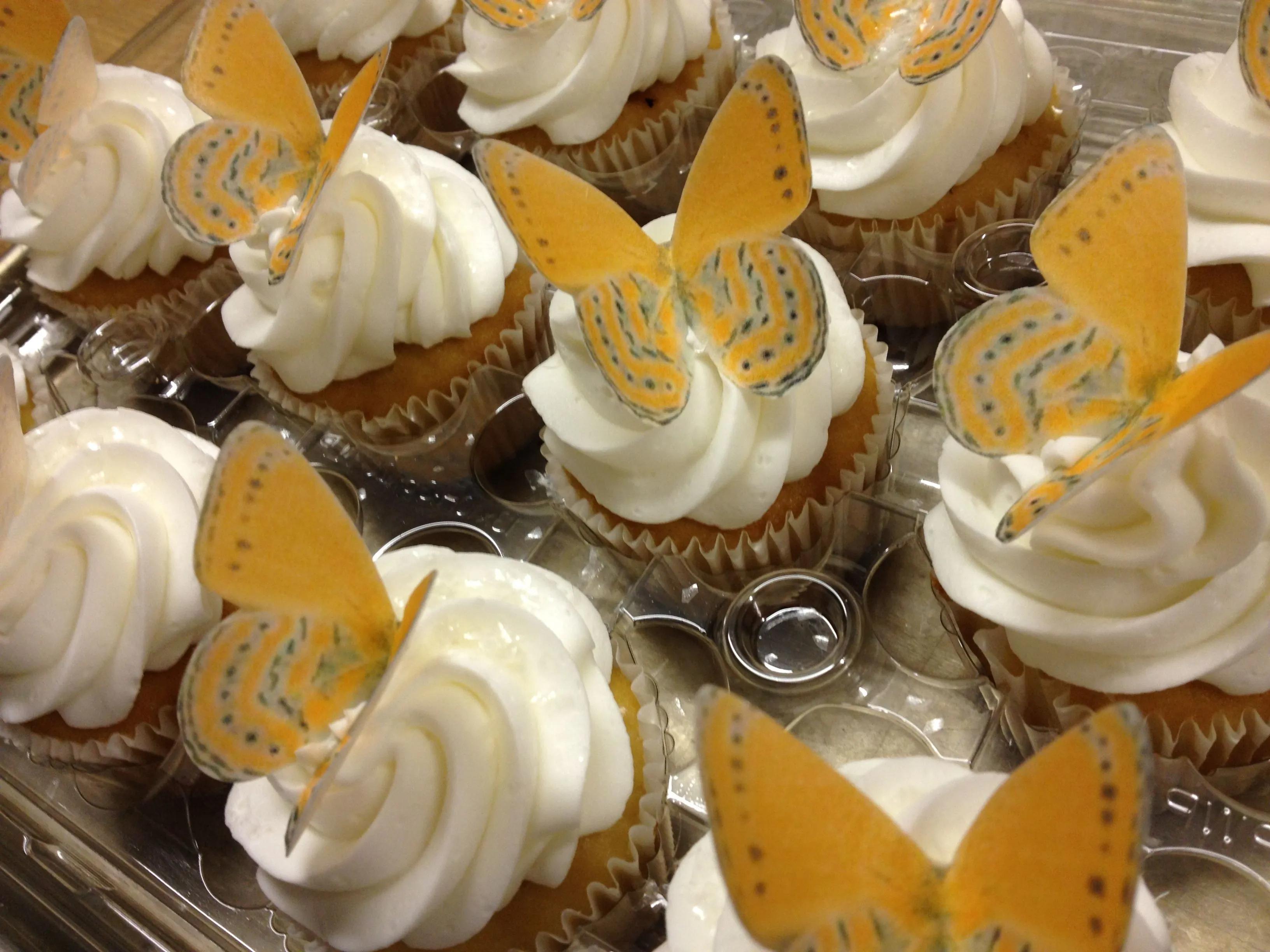 cupcakes with white frosting and yellow butterflies on them