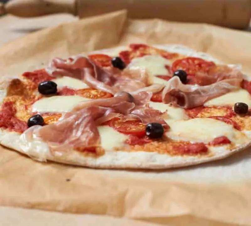 Pizza Parma mit Schinken, Mozzarella, Tomaten und schwarzen Oliven