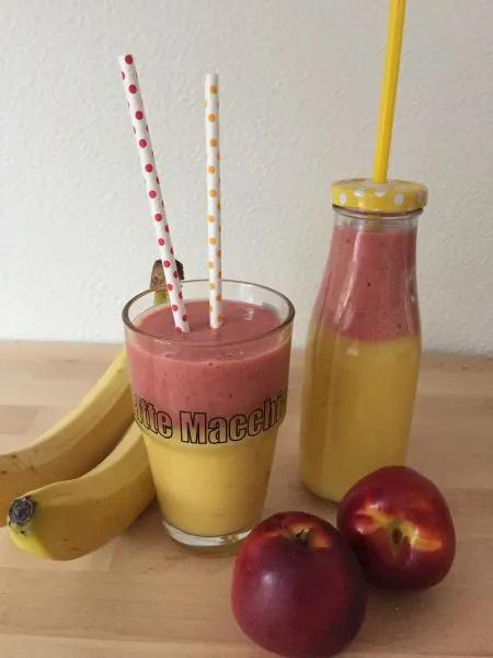 there is a smoothie in a glass next to two bananas and an apple on the ...