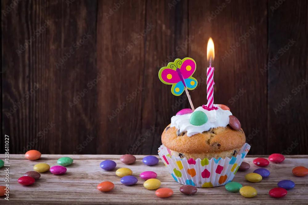 Muffin mit Kerze und Schoko-Dragees Stock Photo | Adobe Stock