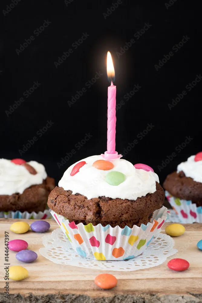 Schokoladen Muffin mit Kerze, Sahne und Schokolinsen Stock-Foto | Adobe ...
