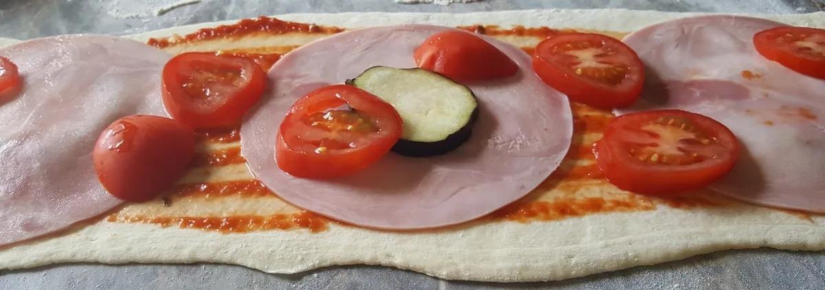 Pizza gerollt mit Schinken, viel Käse und frischen Tomaten