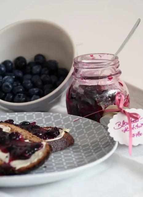 blueberries and bread are on a plate next to a jar of jam