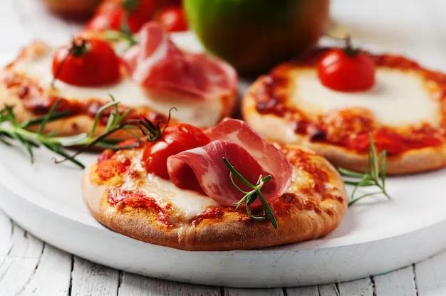 Mini-pizza mit mozzarella, schinken und tomate | Premium-Foto