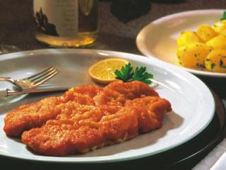 A photo of a golden fried Wiener Schnitzel served with a lemon wedge, parsley, and potato salad